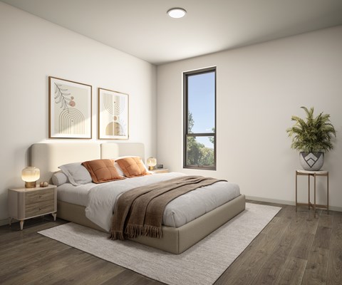 A bedroom with a large bed, a window, and a potted plant.