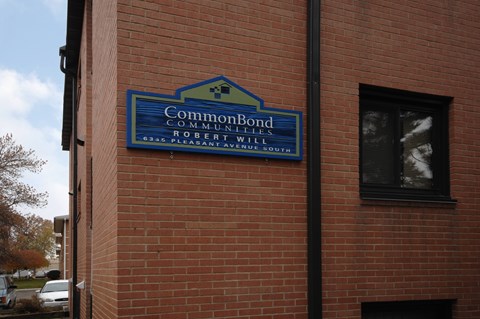 A blue sign on a brick building that says "CommonBond Communities Robert Williams".