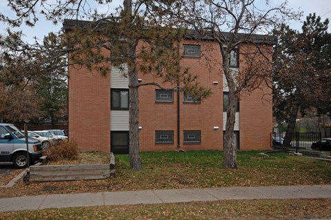 A red brick building with a tree in front of it.