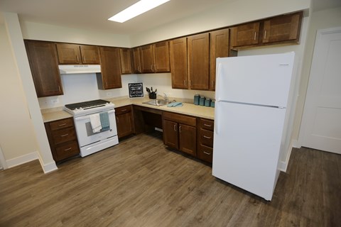 A kitchen with a white fridge, brown cabinets and a white stove.