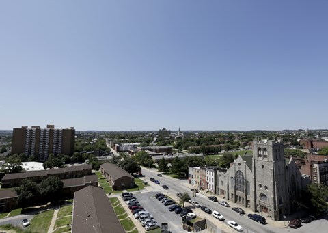 A church with a tall steeple stands in front of a parking lot.