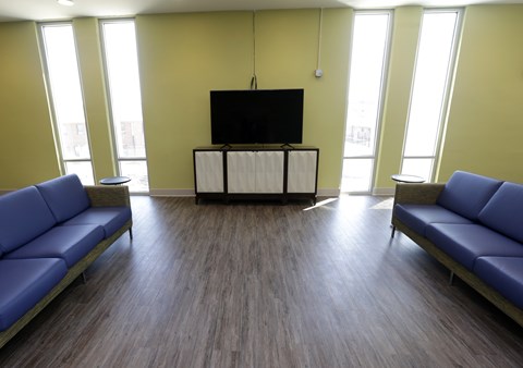 A room with a television and two blue couches.