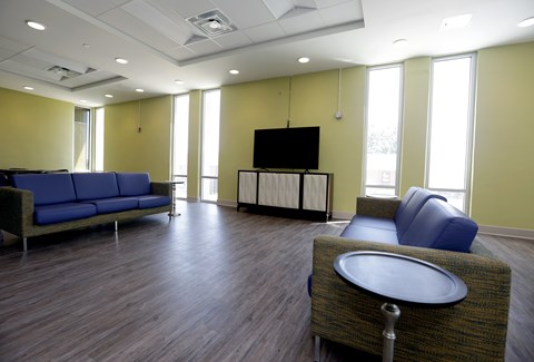 A room with a blue sofa, a grey table and a television.