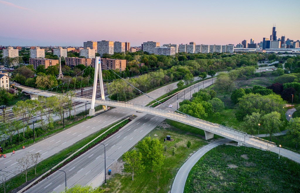 an aerial view of a bridge over highways and a city at dusk