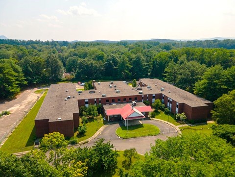 A large red building surrounded by trees and a parking lot.