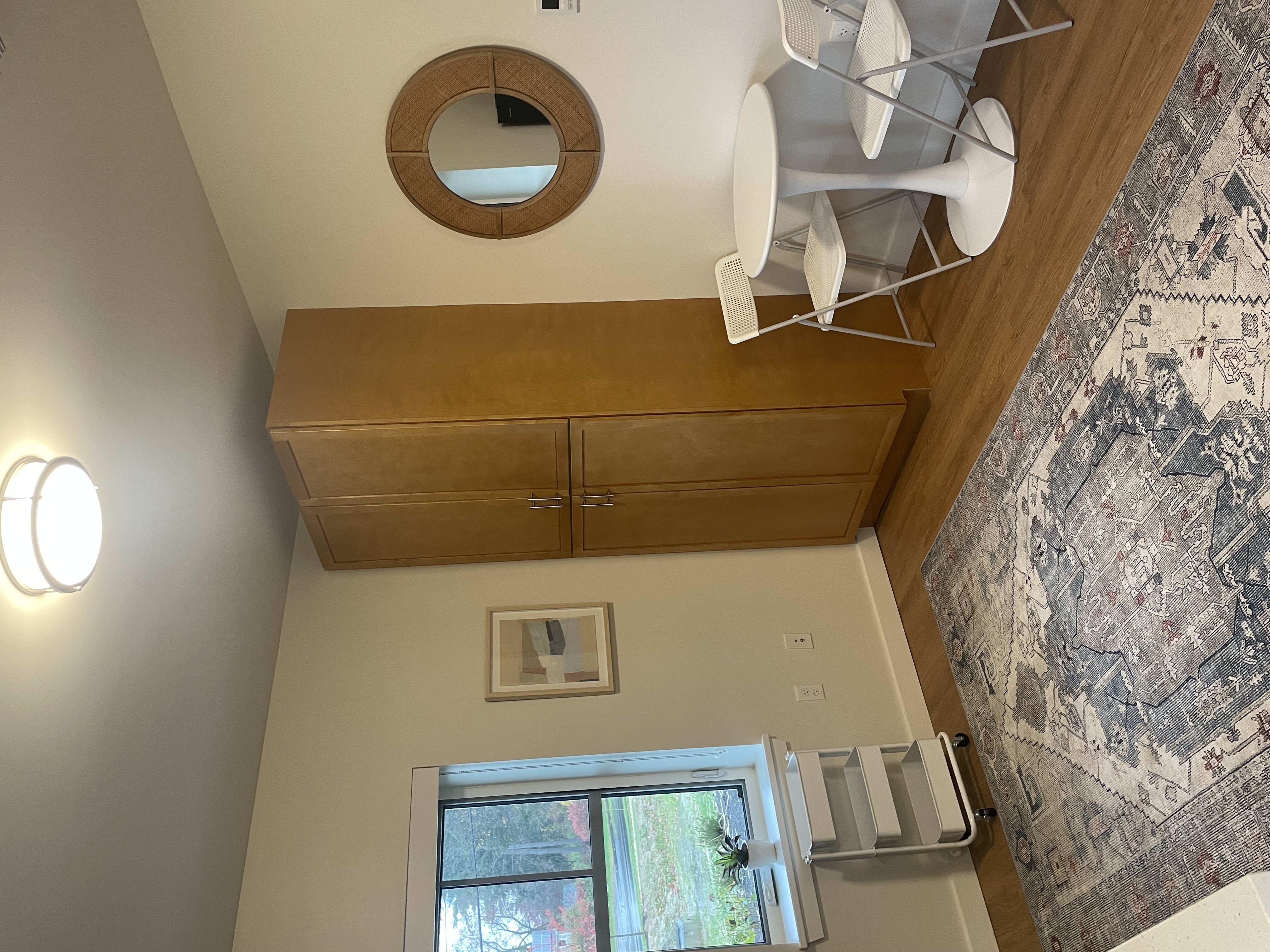 A kitchen with a window and a rug hanging on the wall.