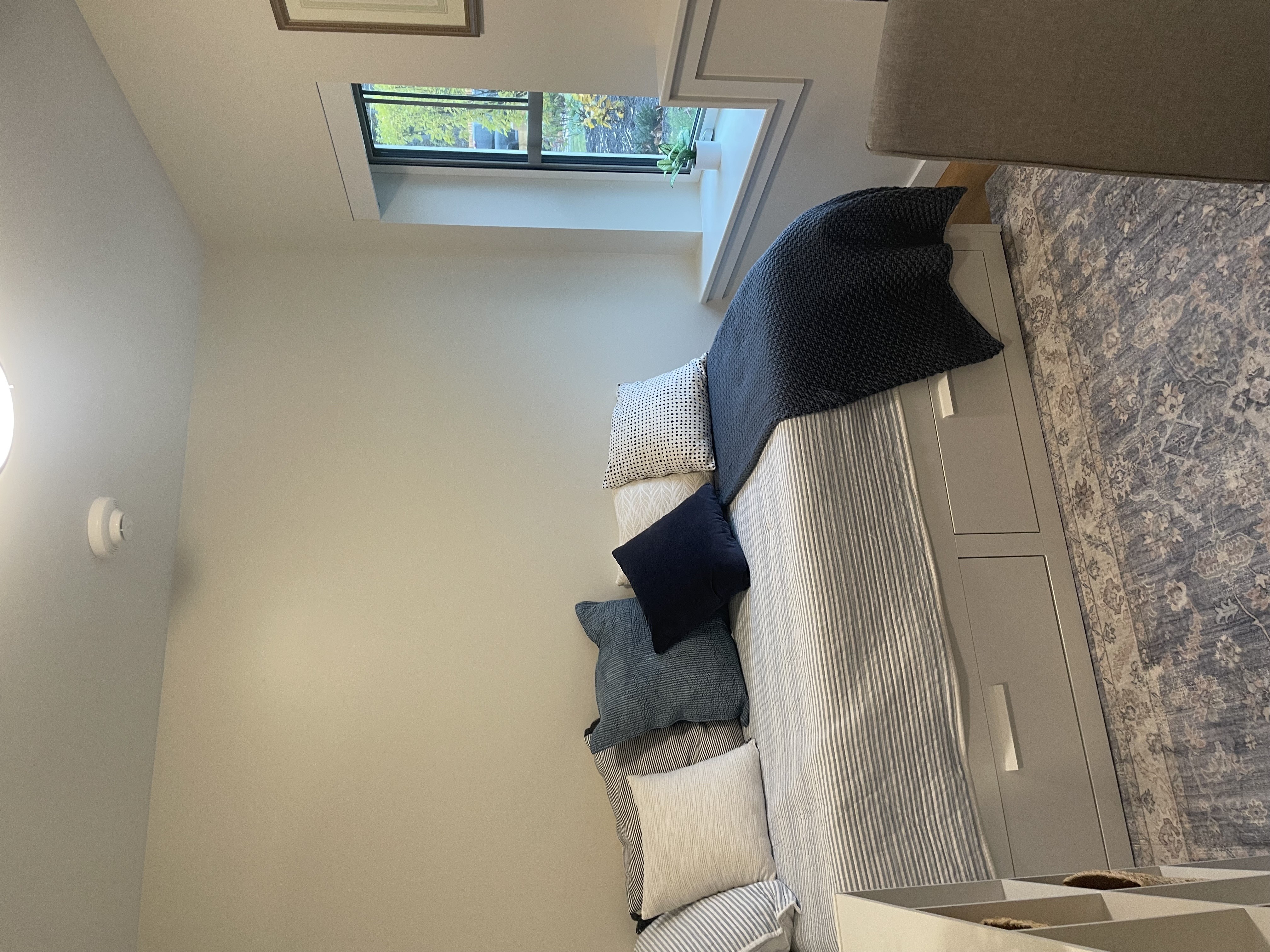 A room with a window and a couch with pillows.