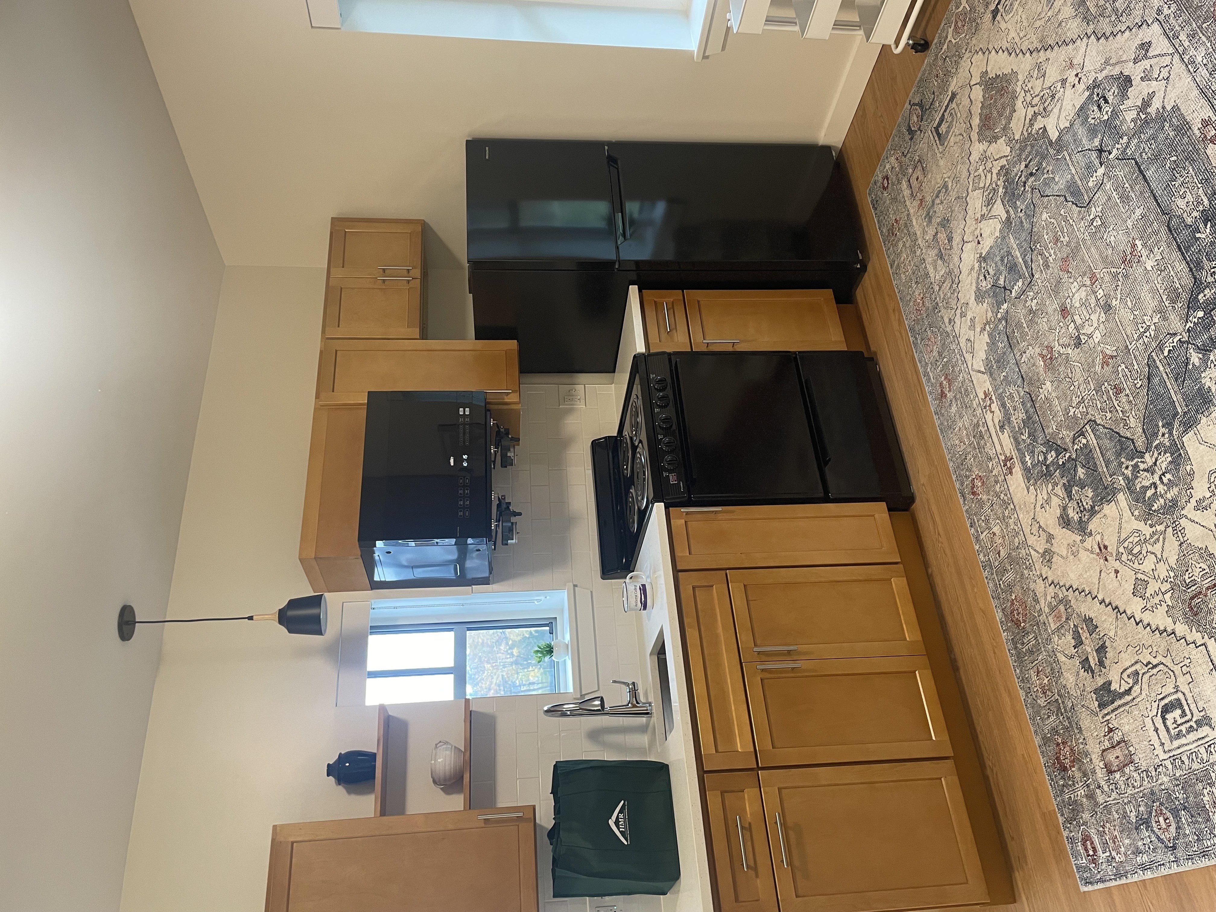 A kitchen area with wooden cabinets and a rug on the floor.