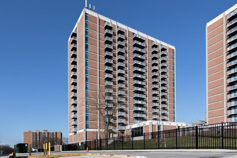 A tall red brick building with balconies on the side.