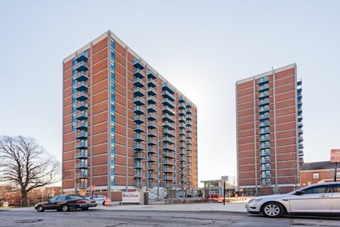 Two red brick buildings with balconies in front of a clear sky.
