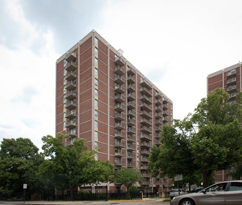 A tall red brick apartment building with balconies on the upper floors.