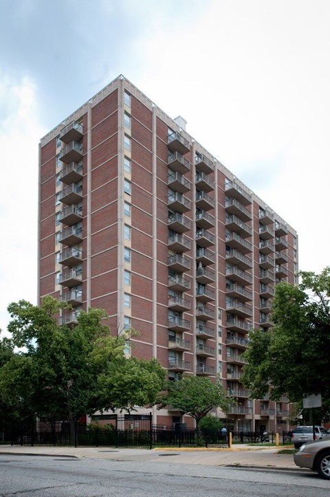 A tall red brick apartment building with balconies on each floor.
