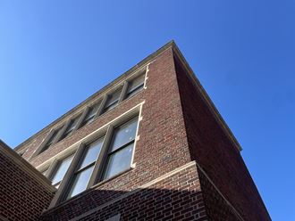 the top of a brick building with windows against a blue sky