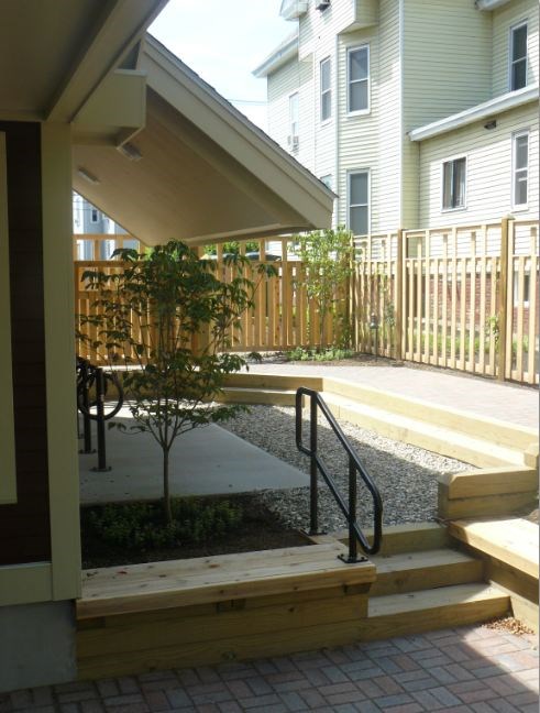 A small tree is planted in a planter in a front yard.