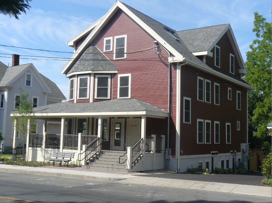 A red two-story house with a porch and a covered entrance.