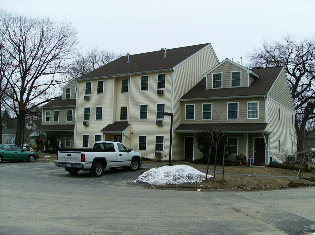 A white house with a green car parked in front.