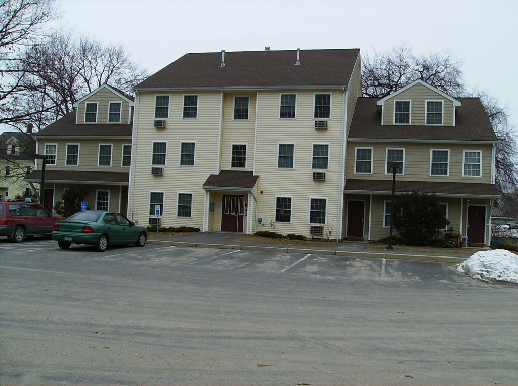 A large white building with a green car parked in front.