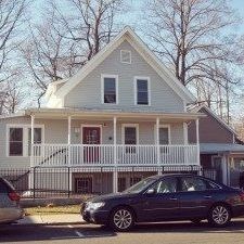 A black car is parked in front of a two-story house.