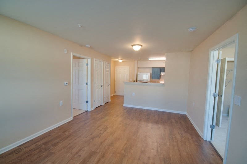 an empty living room and kitchen with wood flooring