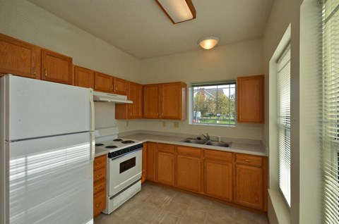 A kitchen with white appliances and wooden cabinets.