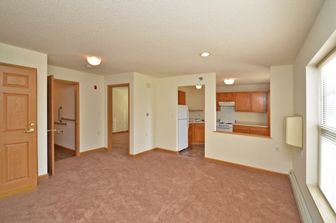 A living room with a brown carpet and white walls.