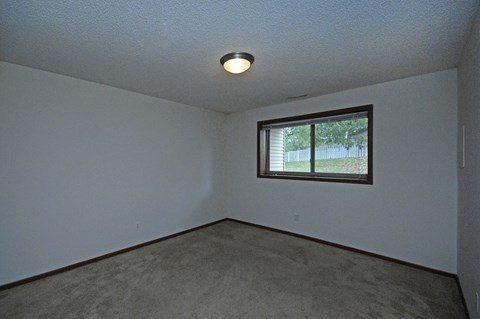 A room with a window and carpeted floor.