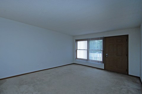 A room with a brown door and a window with blinds.