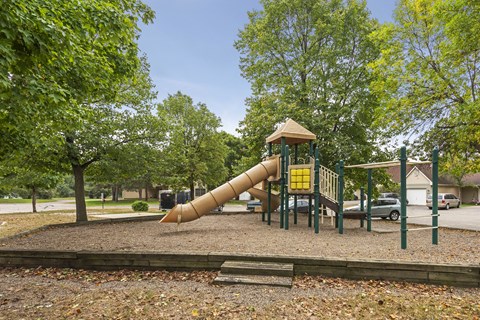 A playground with a yellow slide and a brown roof.