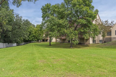 A large grassy area with trees and houses in the background.