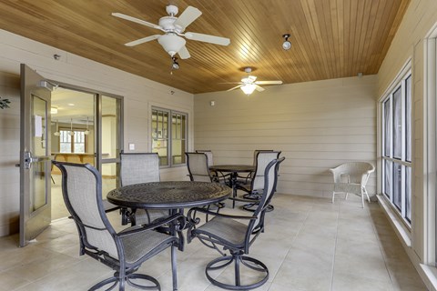 A patio with a table and chairs and a ceiling fan.