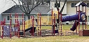 A playground with a yellow slide and a purple slide.