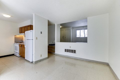 A white refrigerator is in a kitchen with a white wall.
