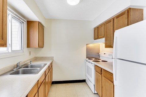 A kitchen with white appliances and wooden cabinets.