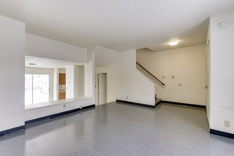 A spacious room with a staircase and a window.