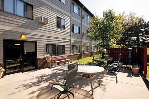 A patio with a table and chairs is in front of a building.