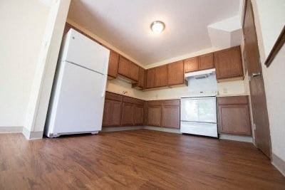 A white refrigerator is in a kitchen with wooden cabinets.