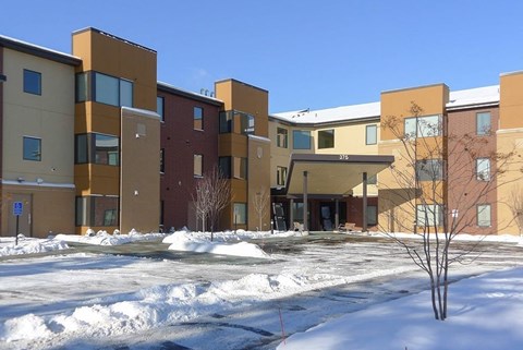 Apartment complex with snow on the ground and trees.