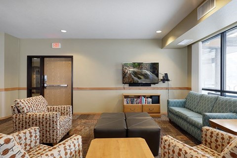 A living room with a couch, chairs, and a television.