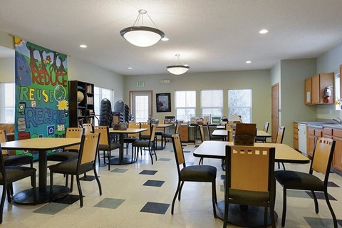 A room with tables and chairs and a sign that says Reduce, Reuse, Recycle.