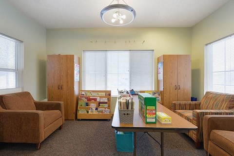A room with a table, chairs, and a bulletin board.