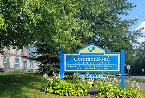 A blue sign for CommonBond Communities is in front of a building.