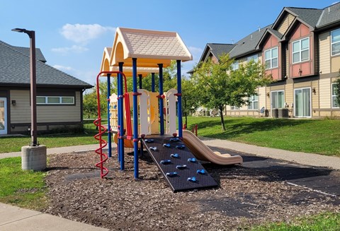 A playground with a slide, swings, and a climbing wall.