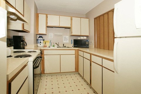 A kitchen with white appliances and wooden cabinets.