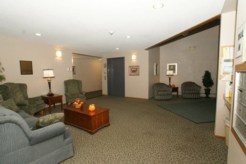 A living room with a grey sofa, a wooden coffee table, and a lamp on a side table.