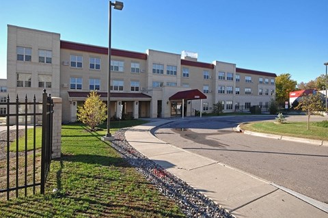 A large building with a red roof and a black fence in front.