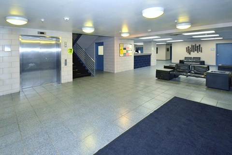 A spacious lobby with a blue carpet and a staircase.