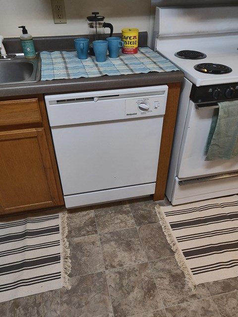 A white dishwasher is in a kitchen next to a white oven.