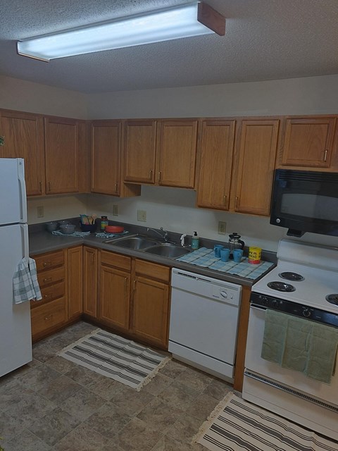 A kitchen with white appliances and wooden cabinets.