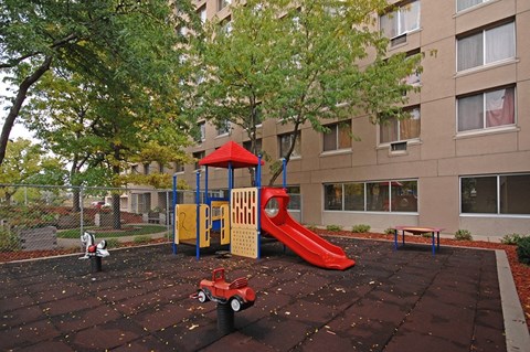 A playground with a red slide and a yellow and blue playhouse.