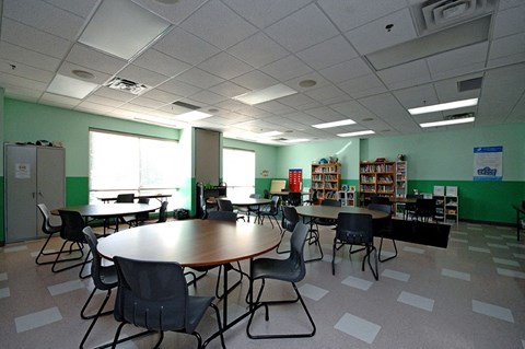 A room with tables and chairs and a bookshelf.